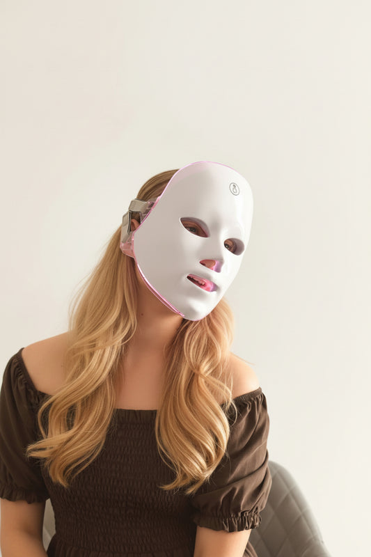 Person wearing a white LED face mask on a plain background
